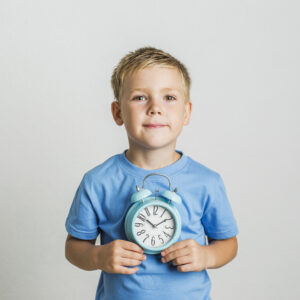 Child holding a blue alarm clock.