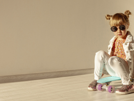 Child sitting on a skateboard indoors.