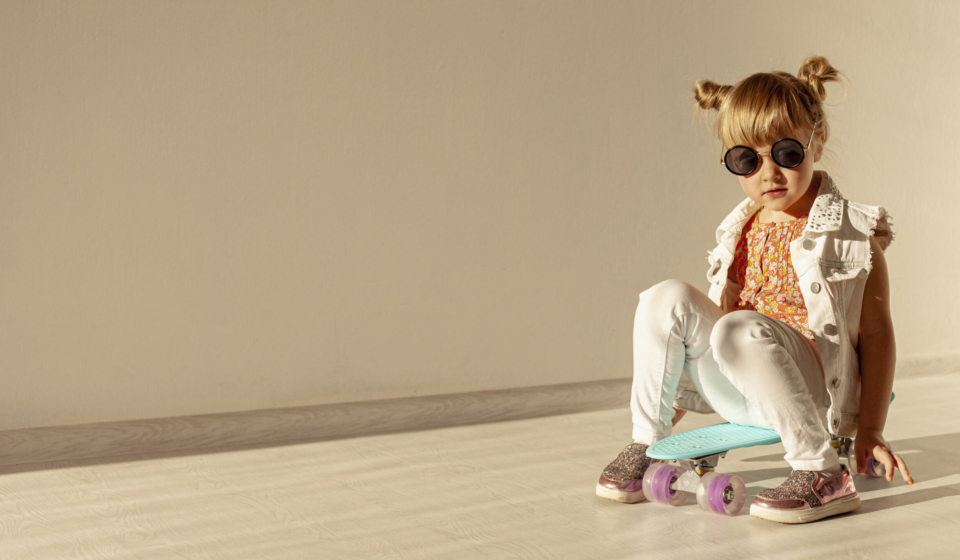 Child sitting on a skateboard indoors.